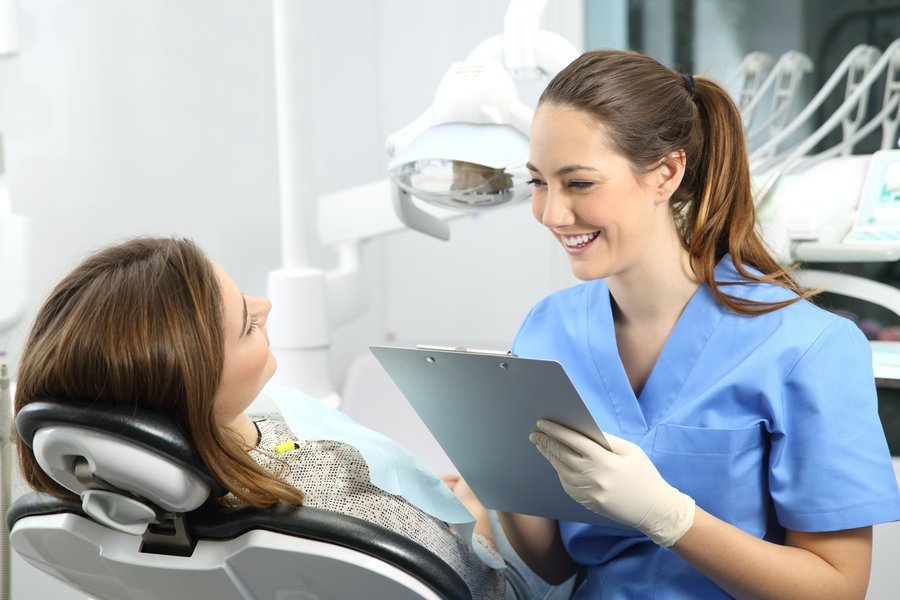 Un asistente dental realizando su labor en un entorno clínico. Asistente dental y paciente en un consultorio moderno.