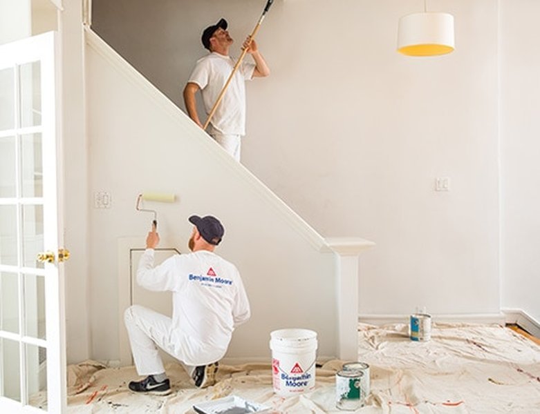 Pintor trabajando en las escaleras interiores de una casa.