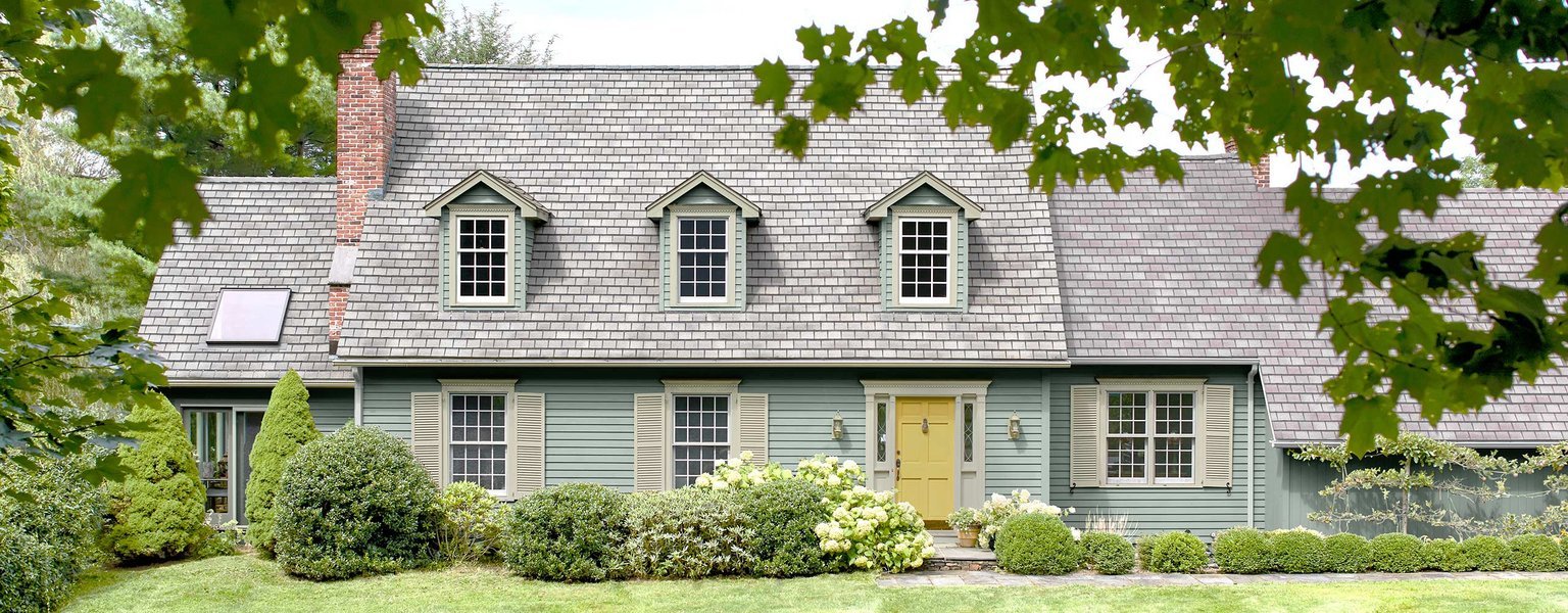 Casa con exterior recién pintado en tonos gris azulado y puerta amarilla.