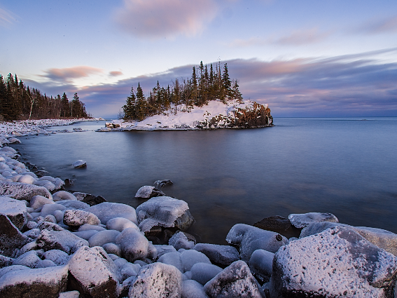 Una orilla rocosa del Lago Superior en Wisconsin, uno de los mejores lagos de los Estados Unidos, y una isla cubierta de nieve al atardecer