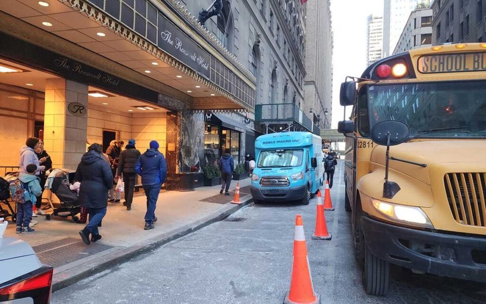 Padres esperando con sus hijos el autobús escolar en Nueva York.